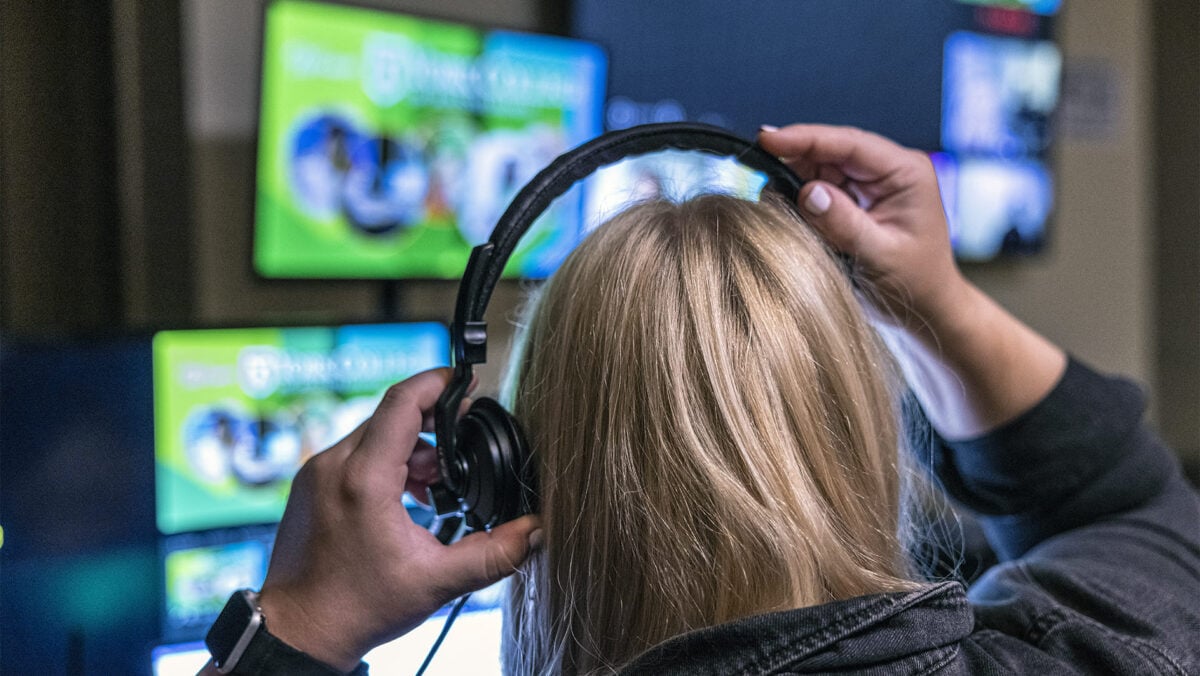 person putting on headset looking at monitors